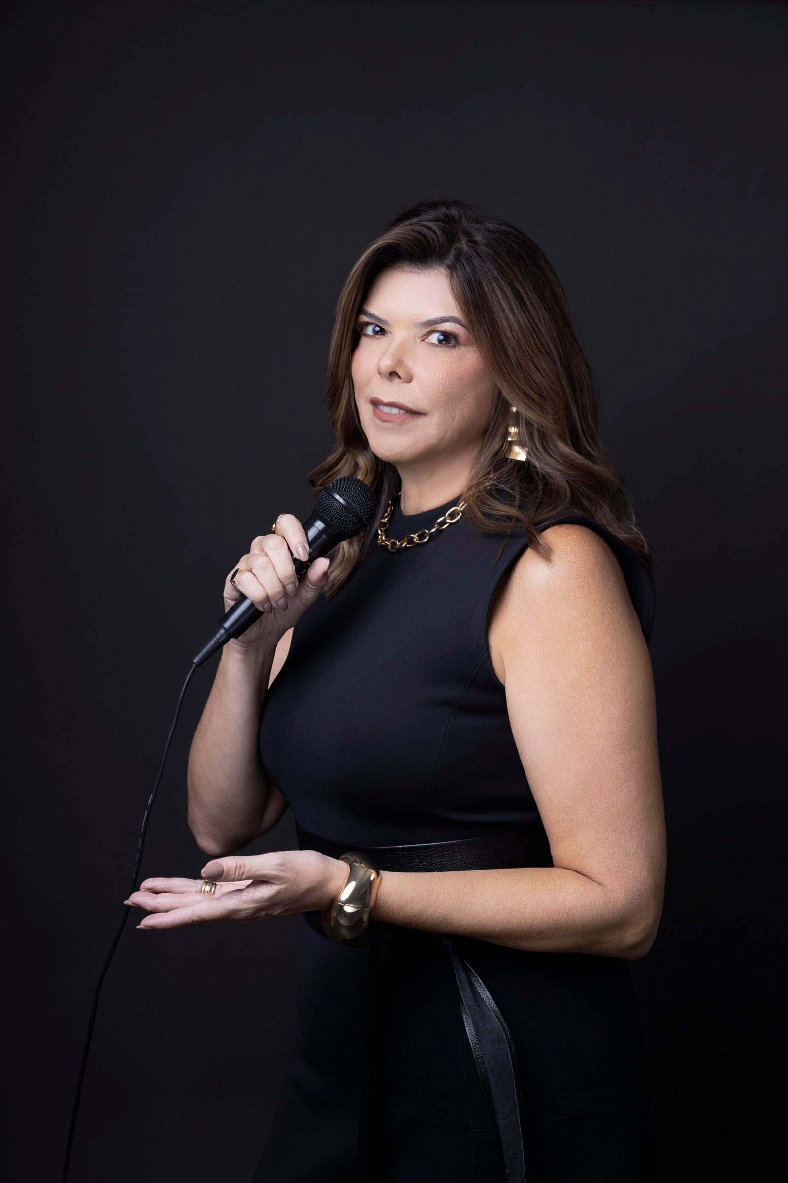 Dra. Silvia Andrade com microfone, em pose de apresentação